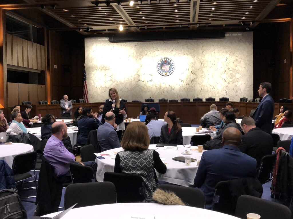 Attendees in hearing room with standing speaker