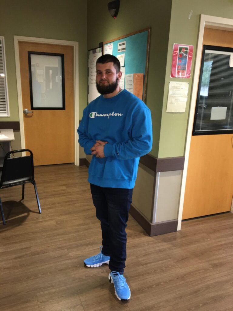 Person standing in hallway wearing blue sweatshirt