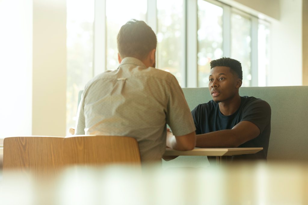 Two men talking at a cafe booth