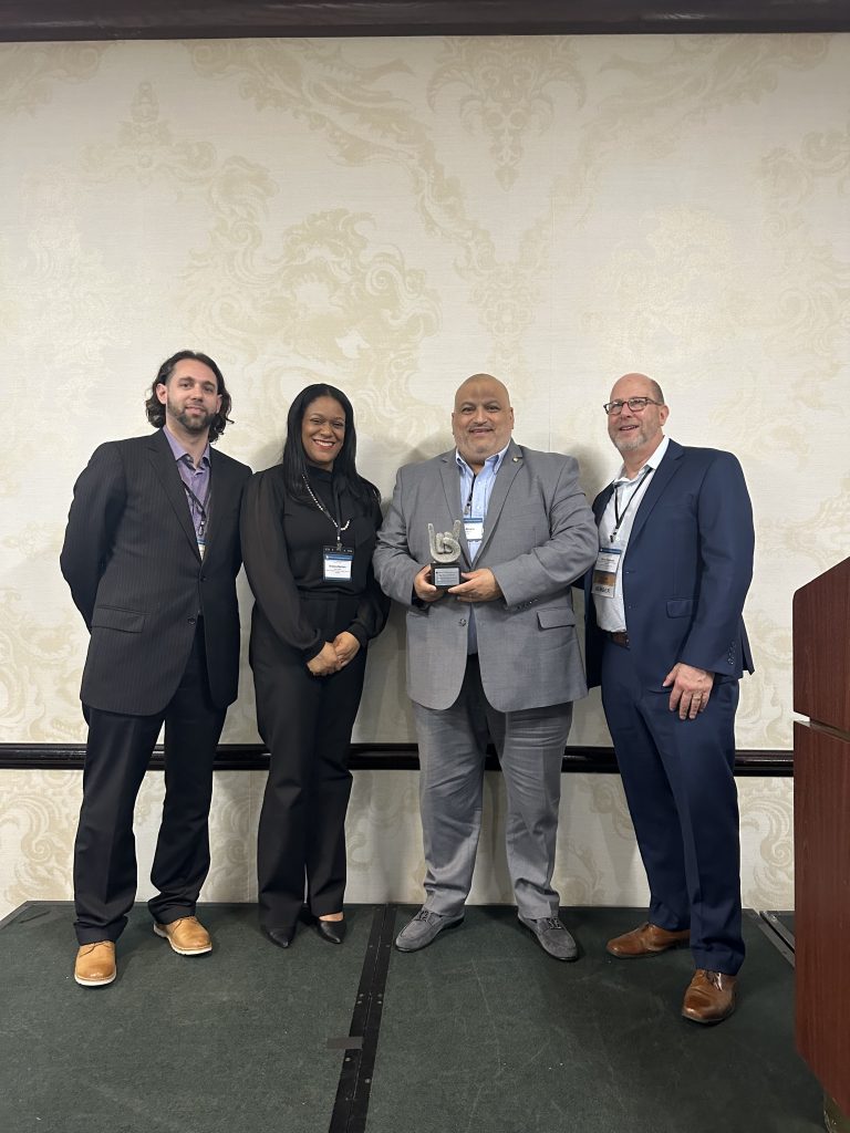 Four professionals posing with award on stage