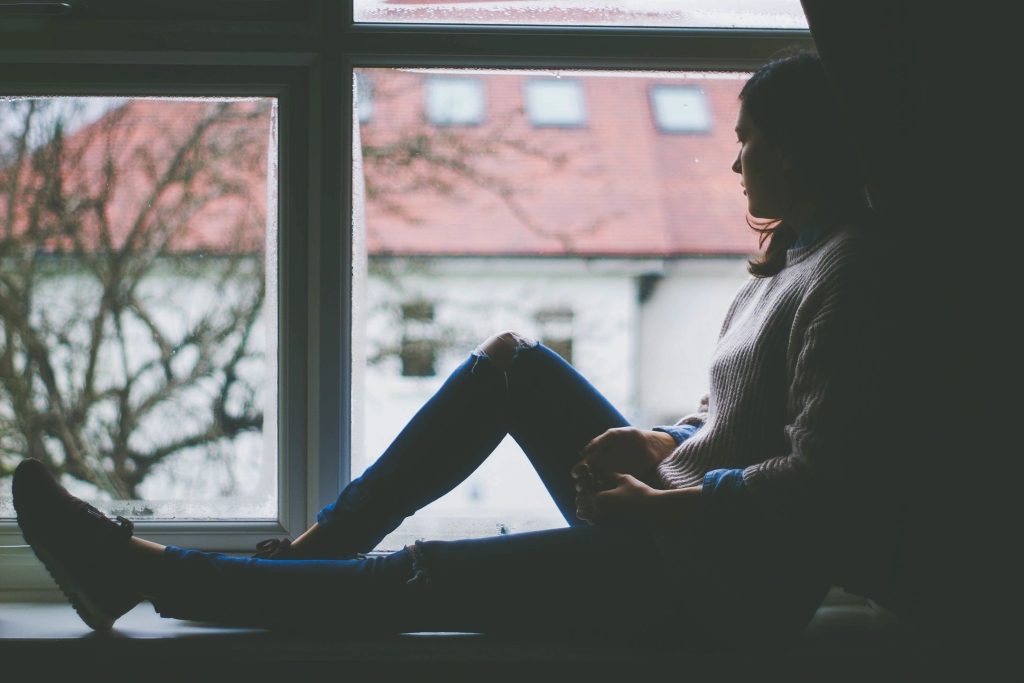 Silhouette of person sitting on windowsill