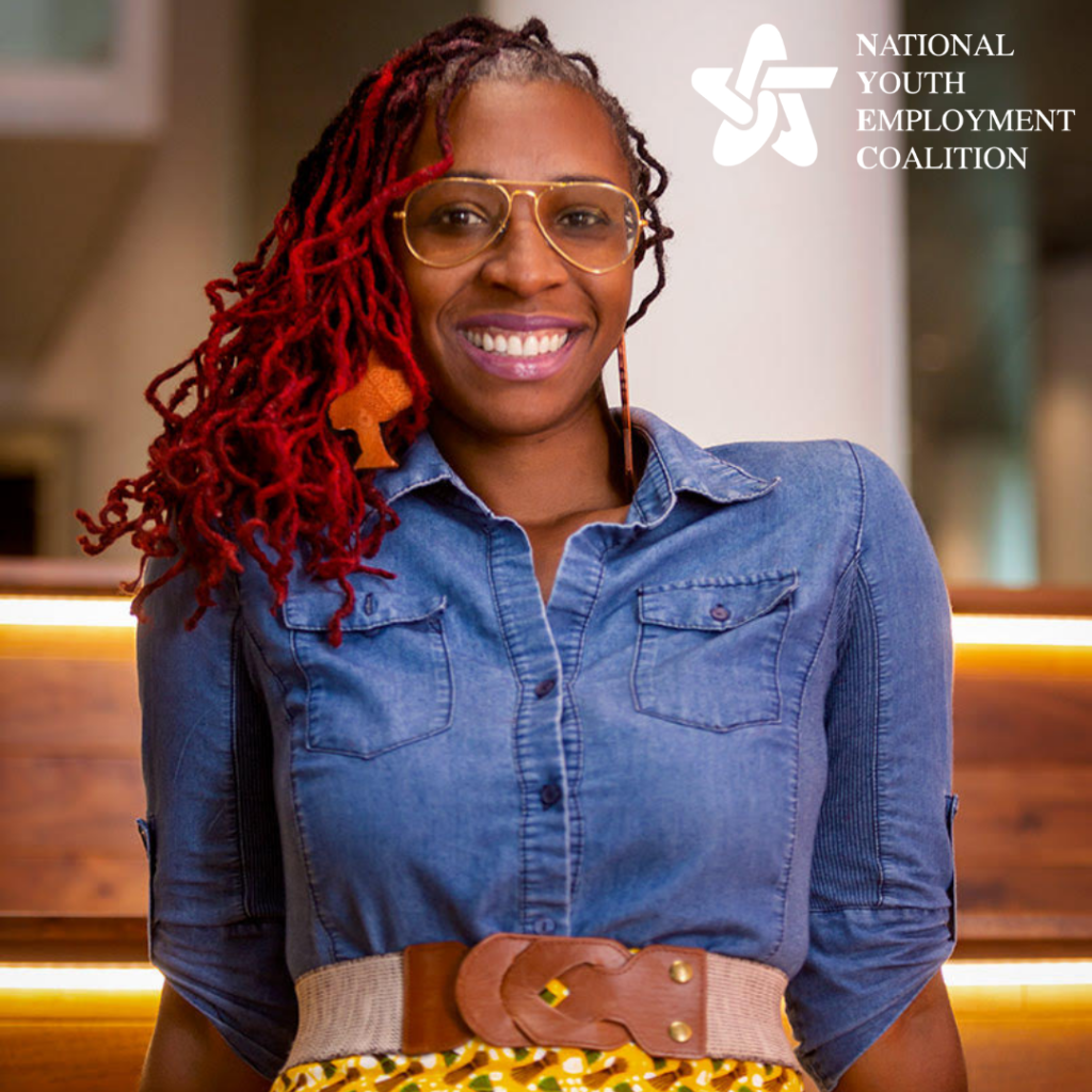 Smiling person with red dreadlocks and glasses