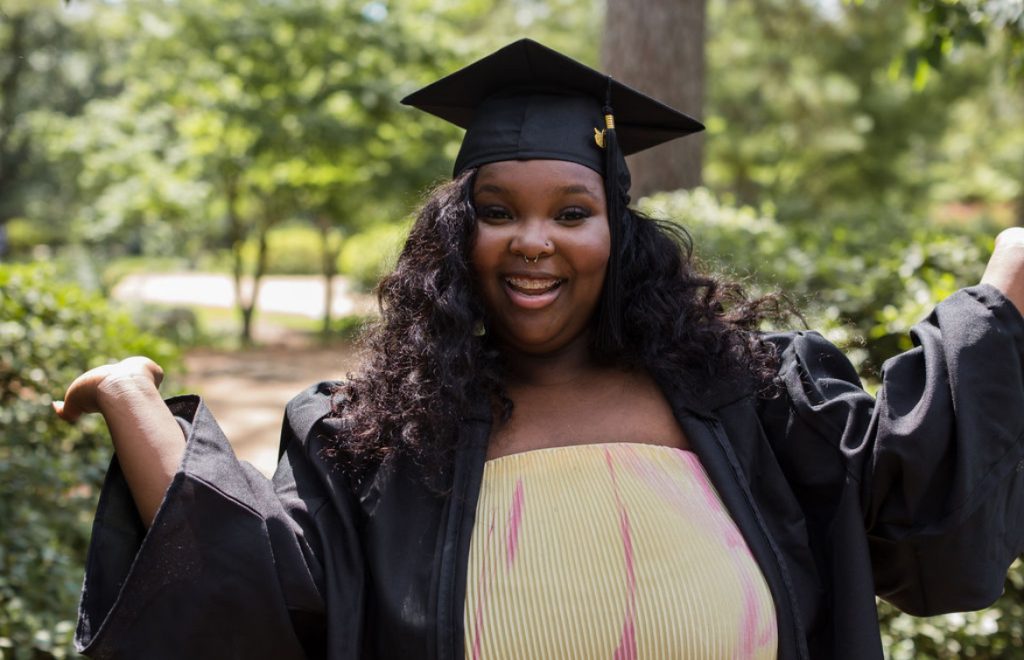 Smiling graduate in cap and gown outdoors