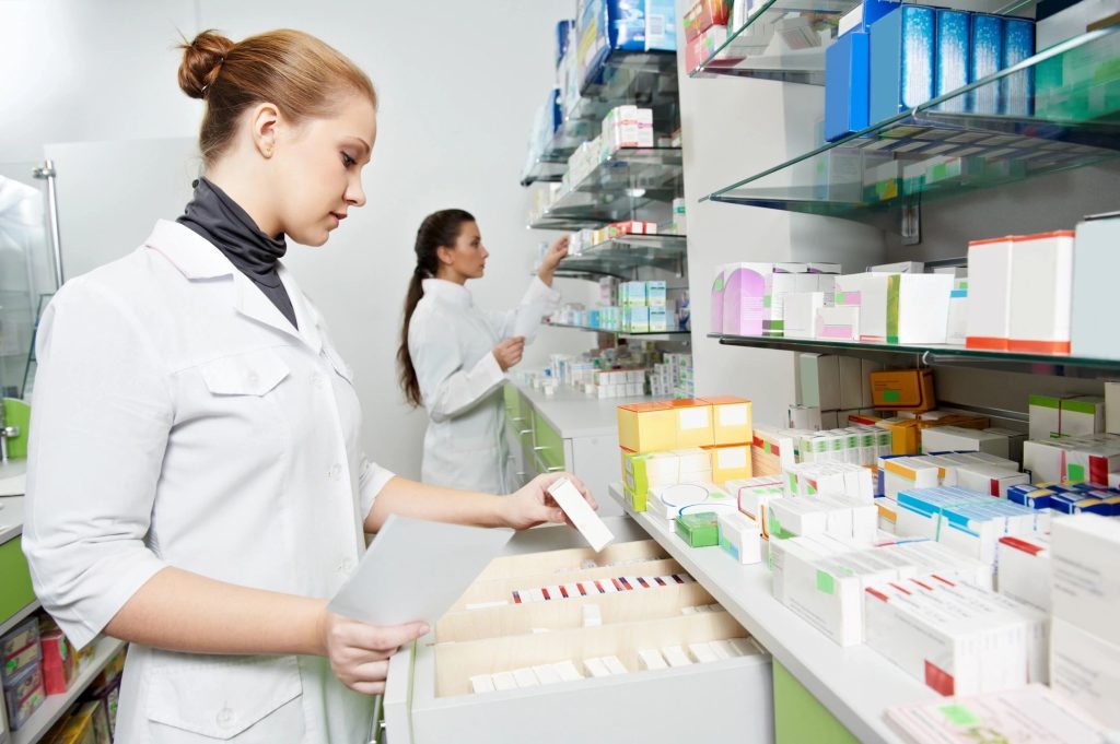 Two pharmacists arranging medication on pharmacy shelves