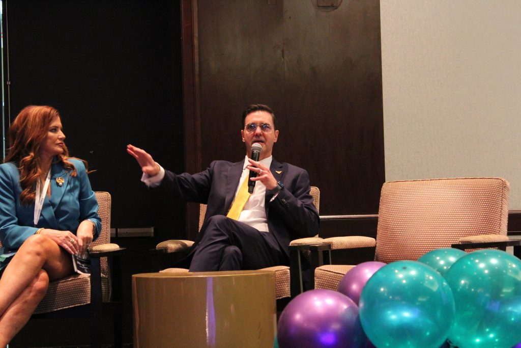 Seated panelists with man speaking into microphone