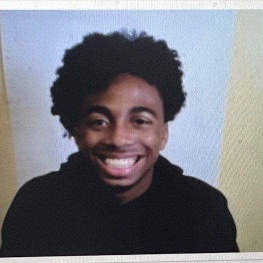 Smiling person with curly hair, light background